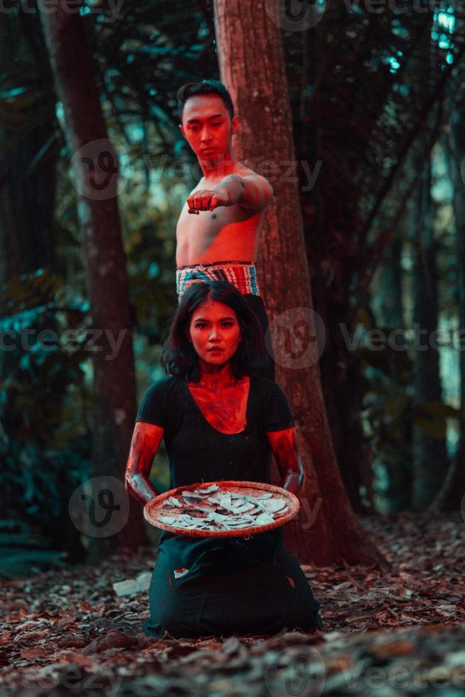 a couple of serial killers have bodies covered in blood and are performing a satanic ritual in the middle of a forest photo