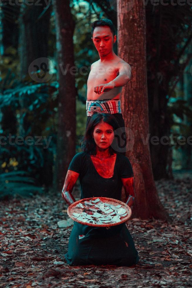 a couple of serial killers have bodies covered in blood and are performing a satanic ritual in the middle of a forest photo