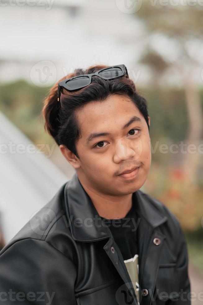 el cara de un muy tonto asiático hombre con Gafas de sol en su cabeza mientras relajante en un café foto