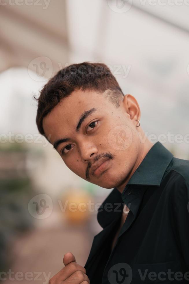 an Asian man with a handsome face and mustache wearing a black shirt while relaxing photo