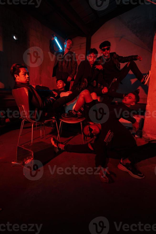 a group of Asian teenagers in black clothes posing very naughty with their friends in a warehouse with a red light photo