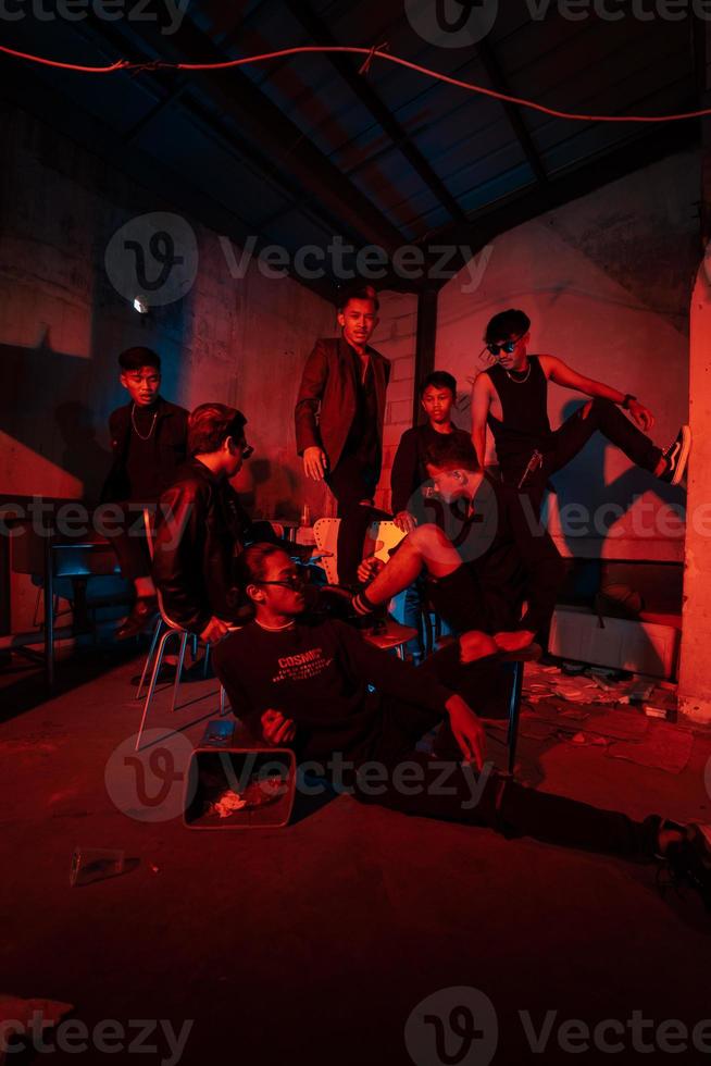 a group of Asian teenagers in black clothes posing very naughty with their friends in a warehouse with a red light photo