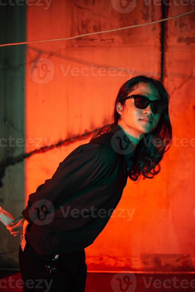 a man with long hair wearing a black shirt and clothes posing very sexy in an old factory photo