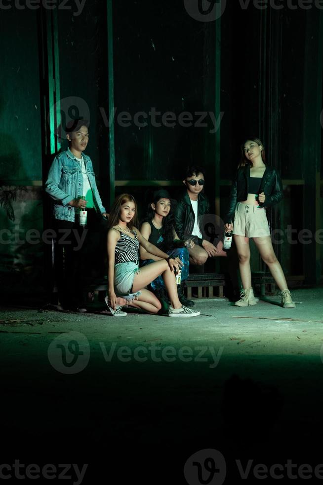 un grupo de adolescentes en peculiar ropa posando juntos como amigos en un disco bar con un muy frio expresión foto