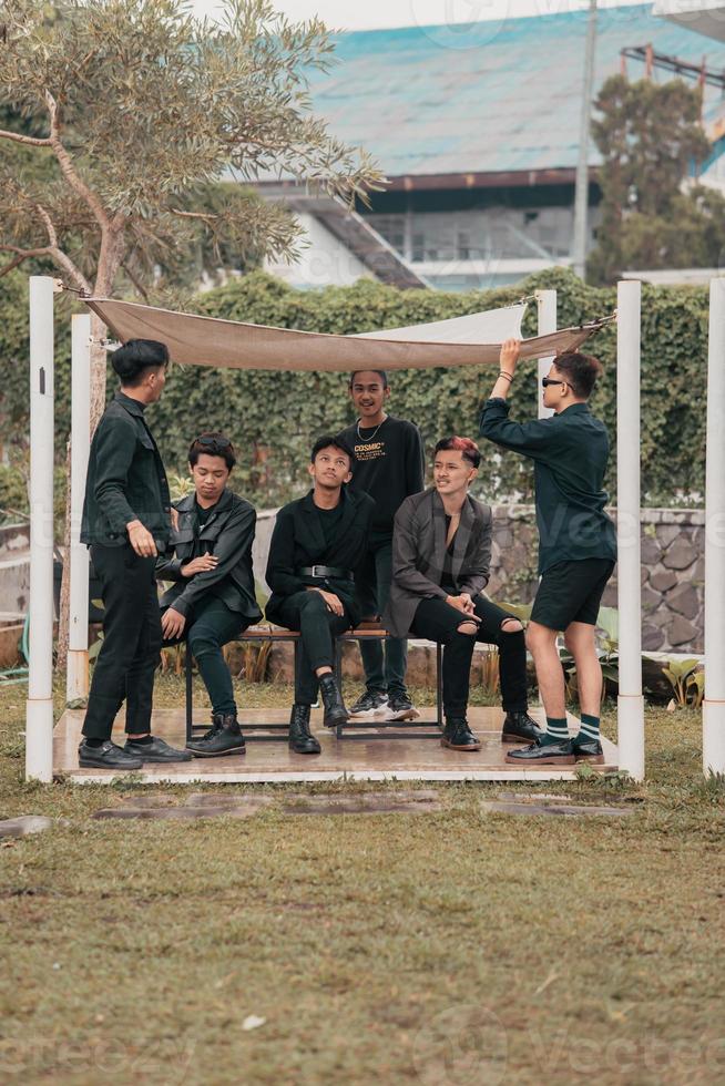 a group of Asian teenagers in black clothes stylized as naughty children while gathering at a cafe photo