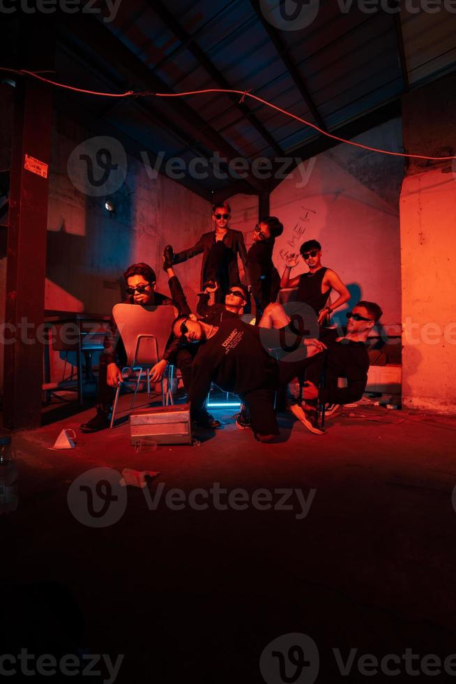 a group of thugs wearing dark clothes and glasses were having fun chatting with their friends in an old building photo