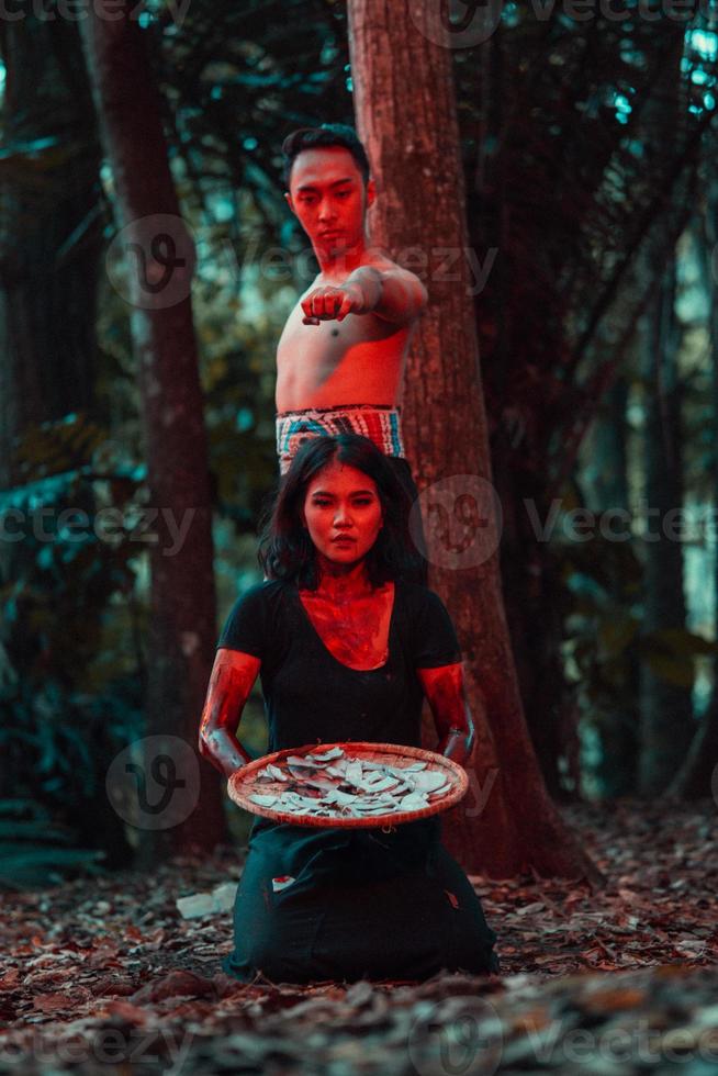 a couple of serial killers have bodies covered in blood and are performing a satanic ritual in the middle of a forest photo