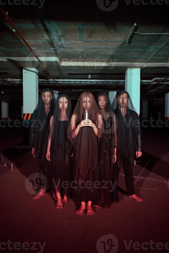 a group of devil worshipers lined up together while holding a candle in the old wake when the ritual will be carried out photo