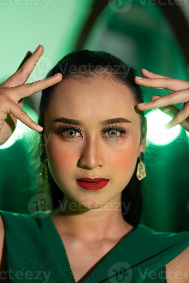  el cara con hermosa maquillaje y rojo labios de un asiático mujer en un verde vestir y joyería   Foto de stock en Vecteezy