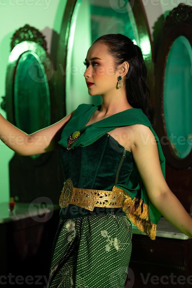 an Indonesian female dancer in an green costume dances in front of a dressing table very beautifully and gracefully photo