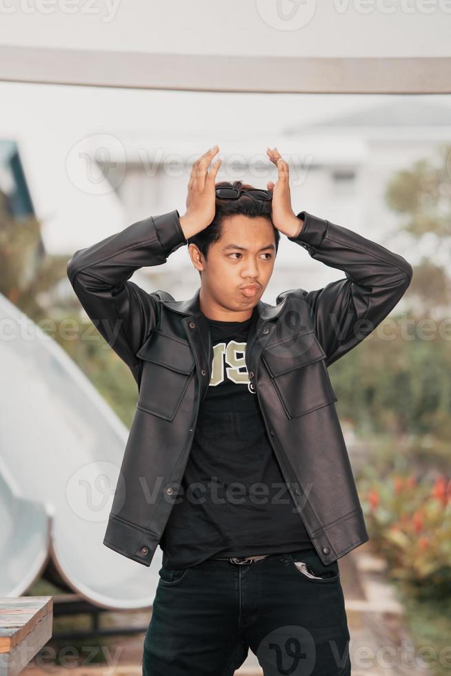 an Asian man is standing beside a cafe table in black leather clothes photo