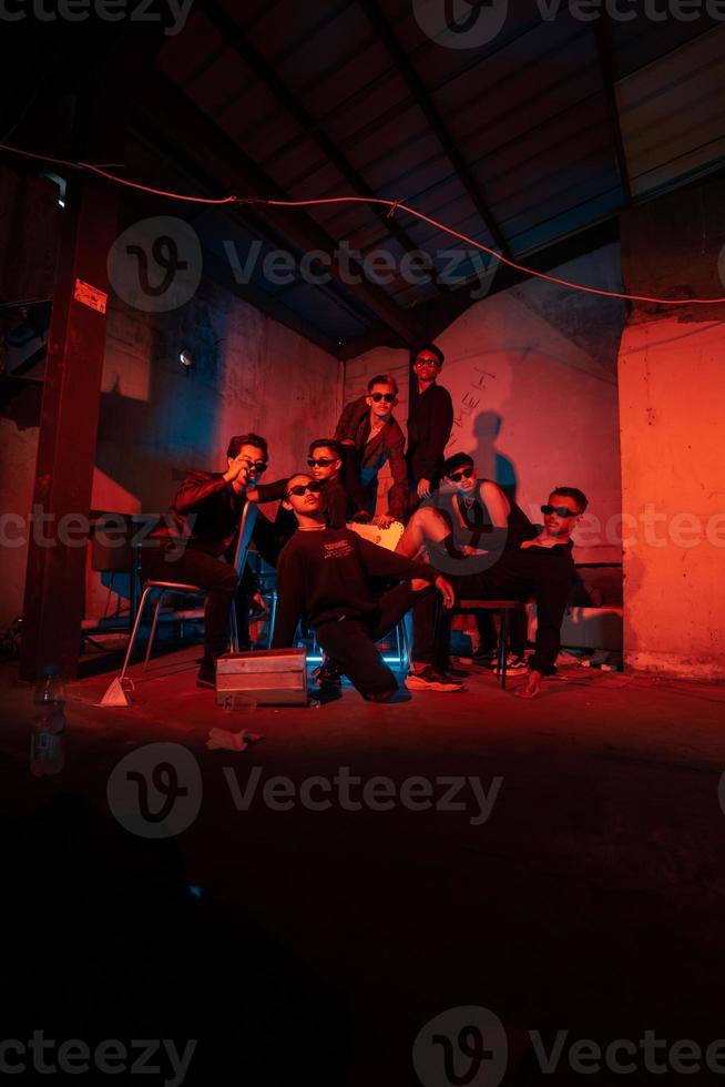 a group of thugs wearing dark clothes and glasses were having fun chatting with their friends in an old building photo