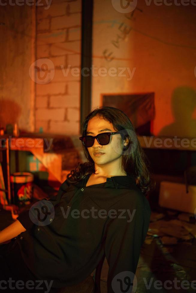 a man with long hair wearing a black shirt and clothes posing very sexy in an old factory photo