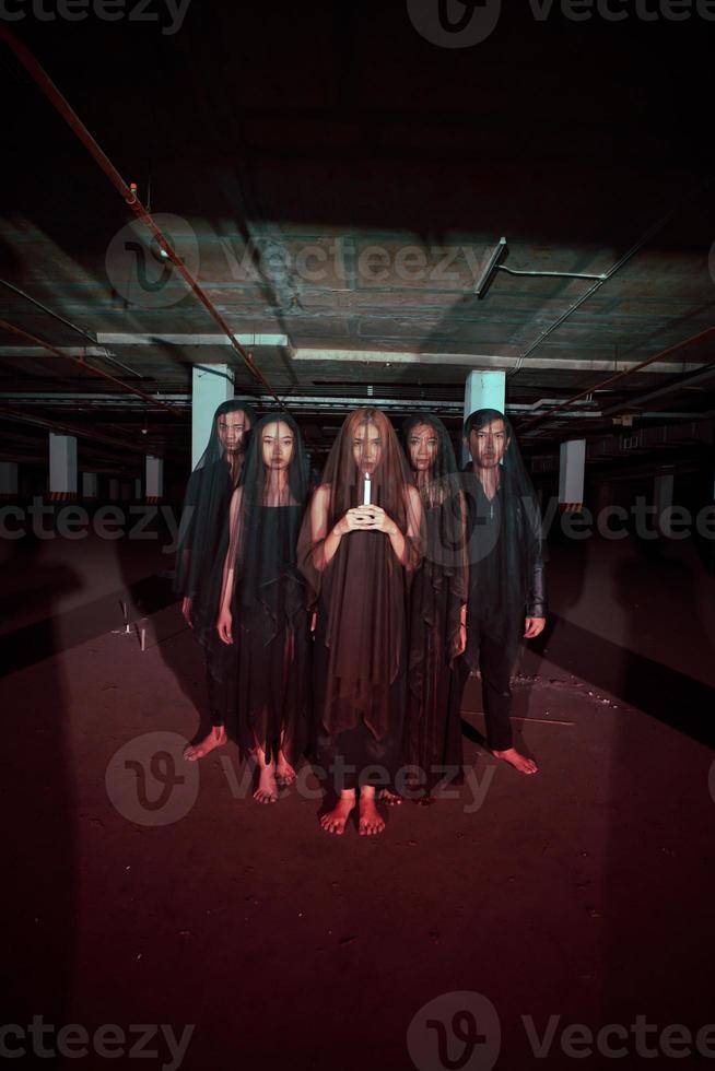 a group of devil worshipers lined up together while holding a candle in the old wake when the ritual will be carried out photo