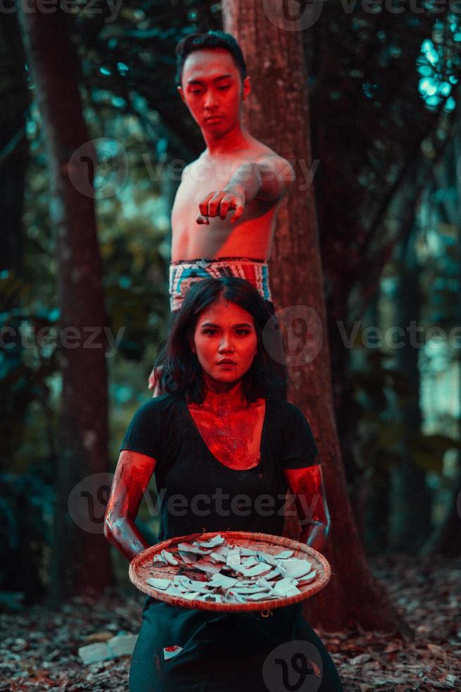a couple of serial killers have bodies covered in blood and are performing a satanic ritual in the middle of a forest photo