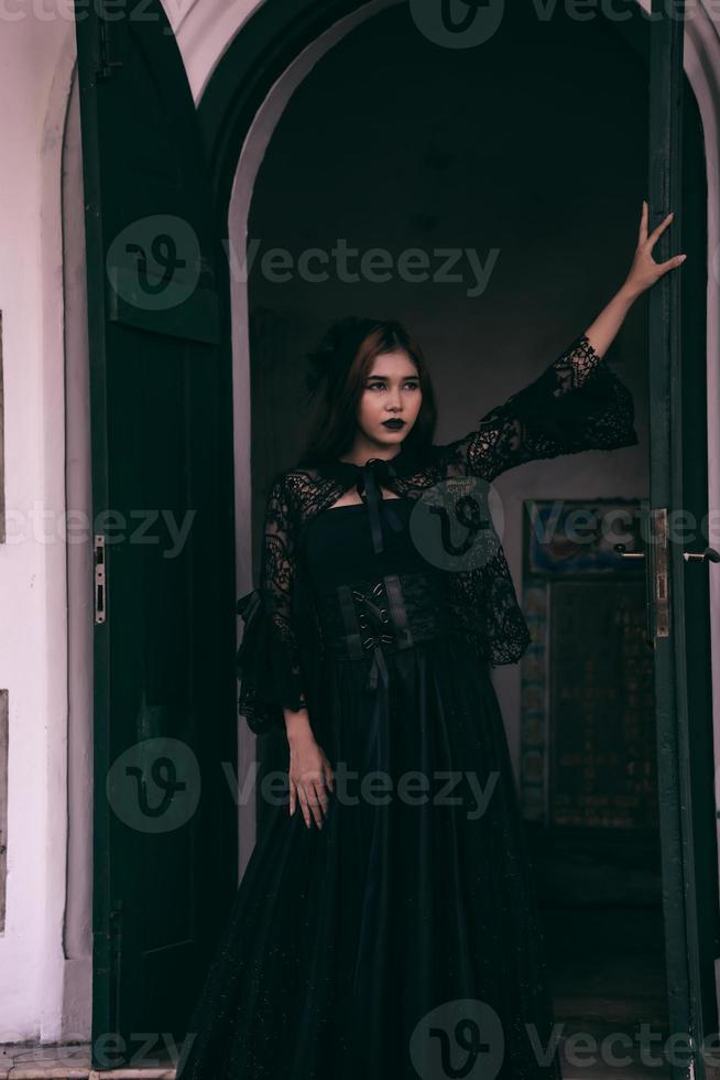 a goth Asian woman dresses up with black make up and wears black clothes like a scary woman at the funeral photo