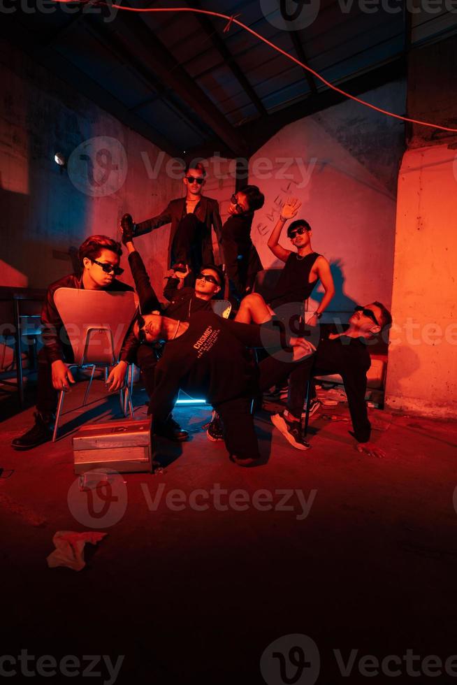 a group of thugs wearing dark clothes and glasses were having fun chatting with their friends in an old building photo