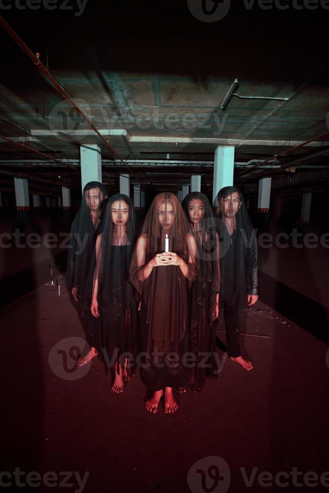 a group of devil worshipers lined up together while holding a candle in the old wake when the ritual will be carried out photo