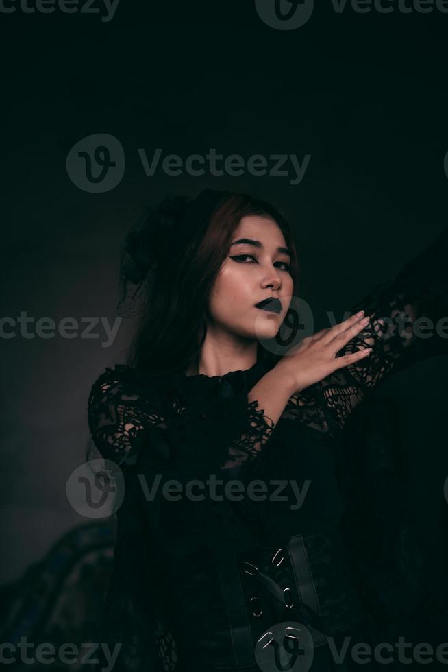 un de miedo asiático mujer con negro labios participación su todo negro ropa cuando visitando el cementerio foto
