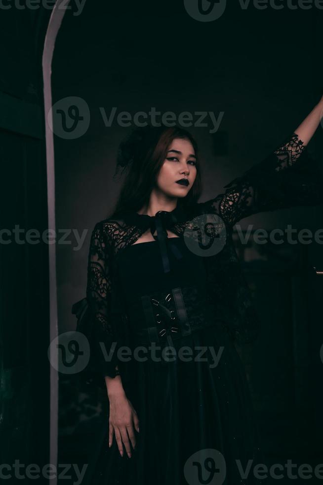 a goth Asian woman dresses up with black make up and wears black clothes like a scary woman at the funeral photo