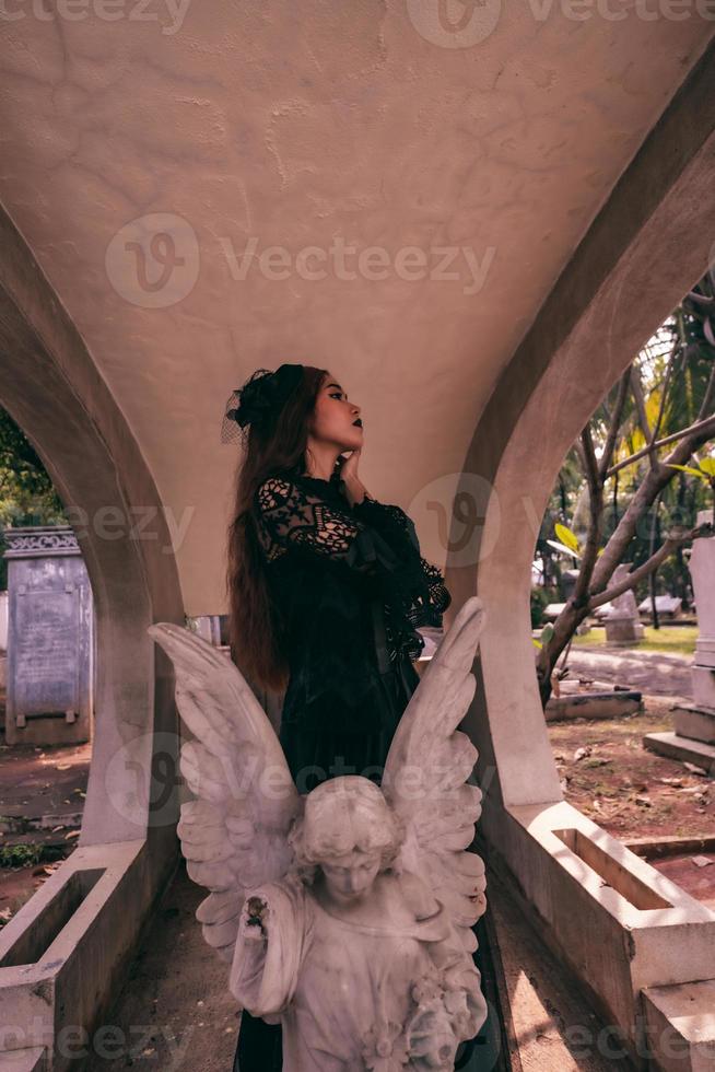 an Asian woman dressed all in black and a scary face was standing over the cemetery photo