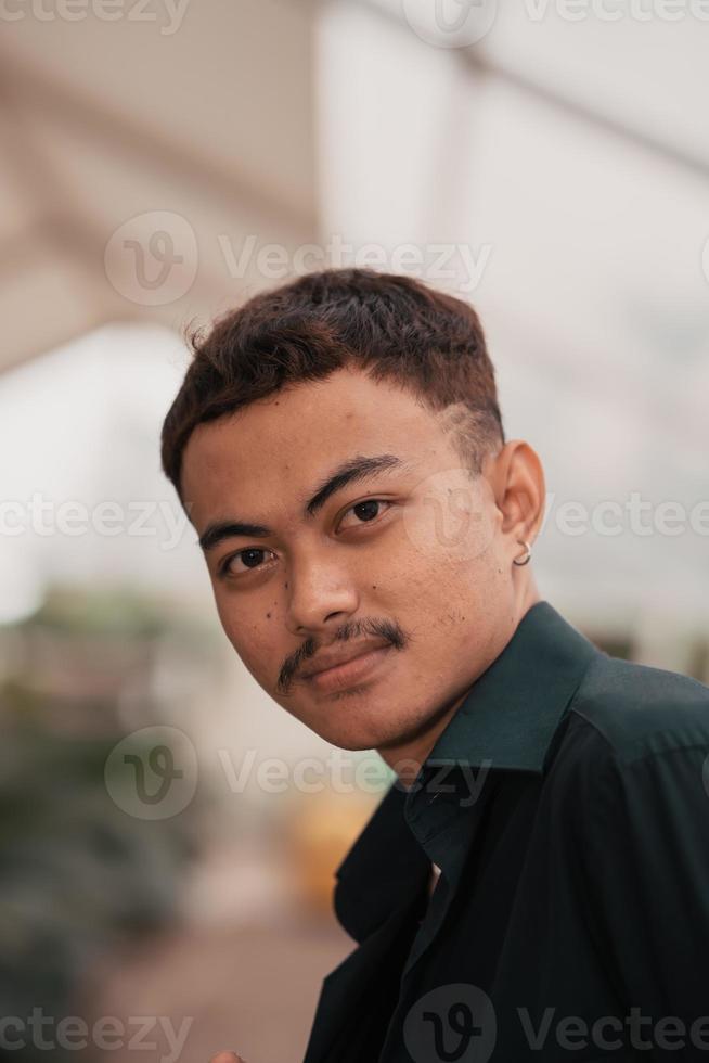 an Asian man with a handsome face and mustache wearing a black shirt while relaxing photo