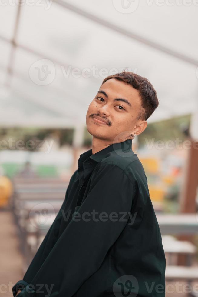 an Asian man with a handsome face and mustache wearing a black shirt while relaxing photo