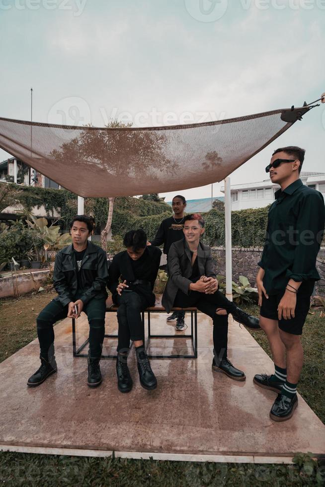 a group of Asian teenagers in black clothes stylized as naughty children while gathering at a cafe photo