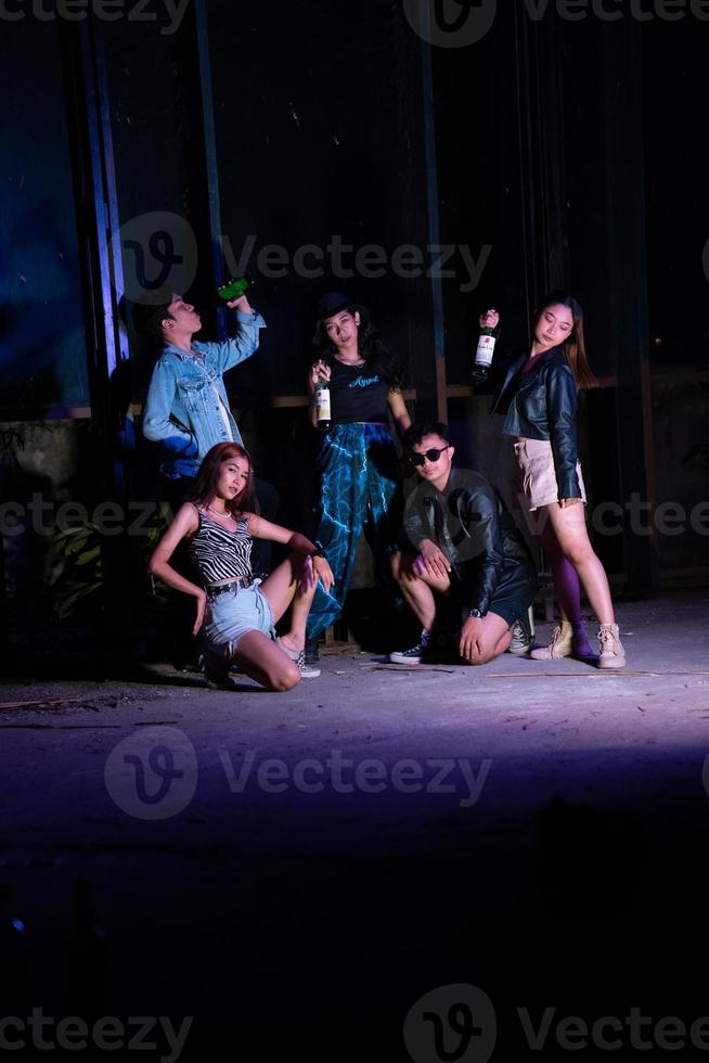 a group of teenagers taking a photo together with a purple light in front of a bar