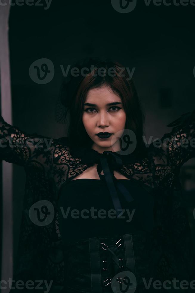 a goth Asian woman dresses up with black make up and wears black clothes like a scary woman at the funeral photo