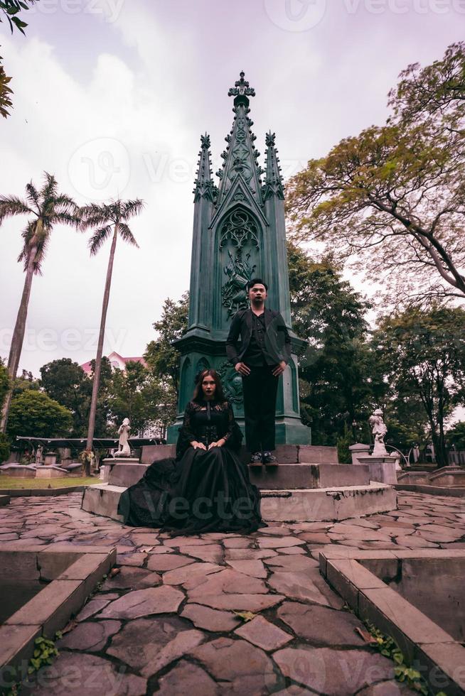 a couple sitting and standing in front of a funeral monument when visiting a friend who has died with a sad expression photo