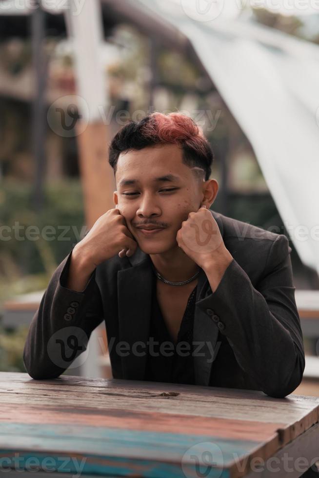 a teenage boy with blond hair poses very funny and cute when wearing a suit photo