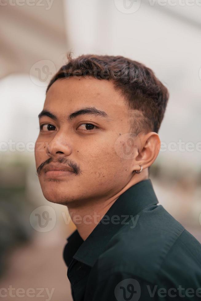 an Asian man with a handsome face and mustache wearing a black shirt while relaxing photo