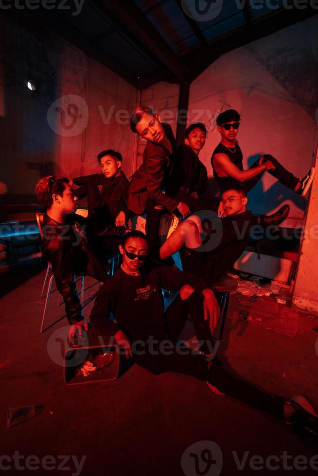 a group of Asian teenagers in black clothes posing very naughty with their friends in a warehouse with a red light photo