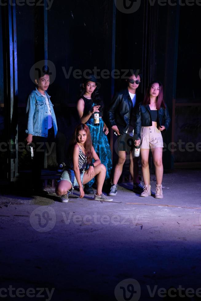 a group of teenagers taking a photo together with a purple light in front of a bar