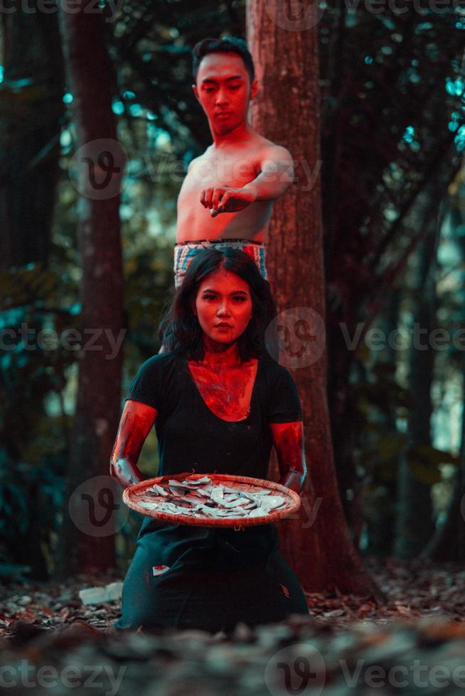 un Pareja de de serie asesinos tener cuerpos cubierto en sangre y son ejecutando un satánico ritual en el medio de un bosque foto