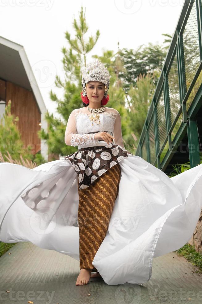 a bride in a white dress is standing in the middle of the bridge with her face full of makeup and a white cloth floating in the air photo