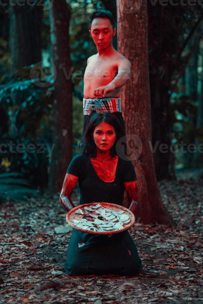 a couple of serial killers have bodies covered in blood and are performing a satanic ritual in the middle of a forest photo