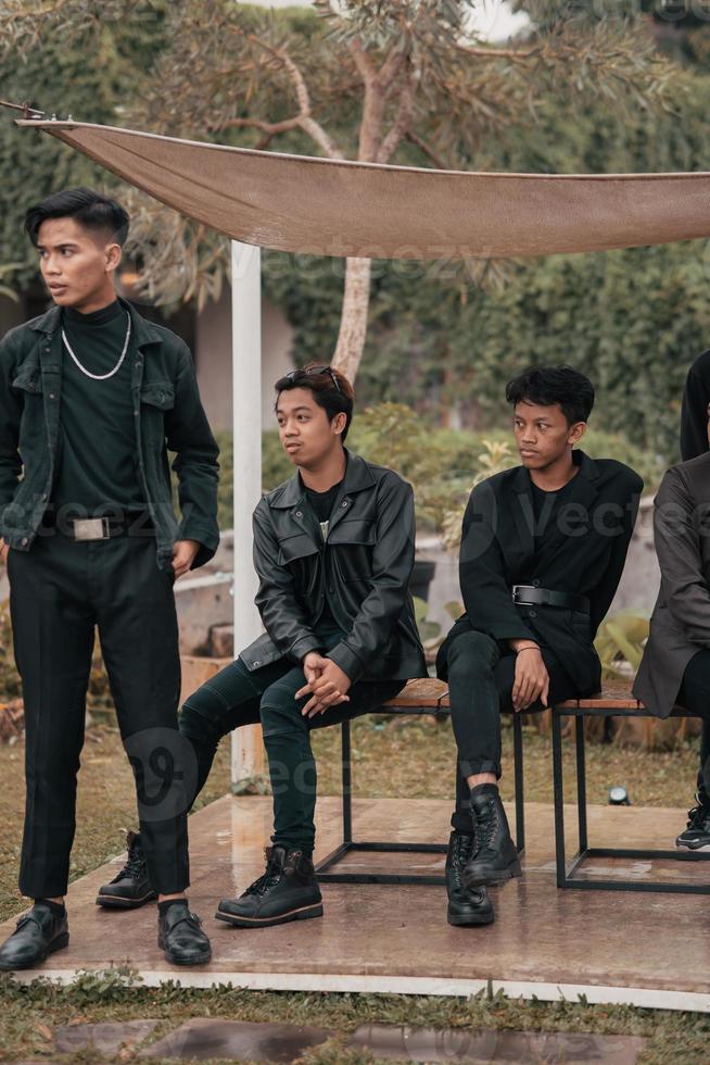 a group of Asian teenagers in black clothes stylized as naughty children while gathering at a cafe photo