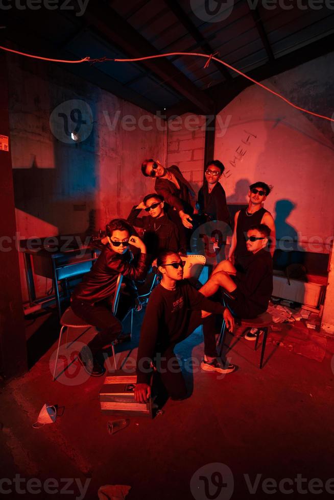 a group of thugs wearing dark clothes and glasses were having fun chatting with their friends in an old building photo