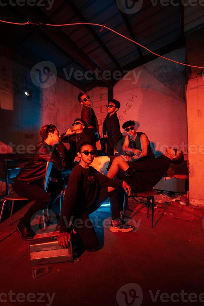 a group of thugs wearing dark clothes and glasses were having fun chatting with their friends in an old building photo