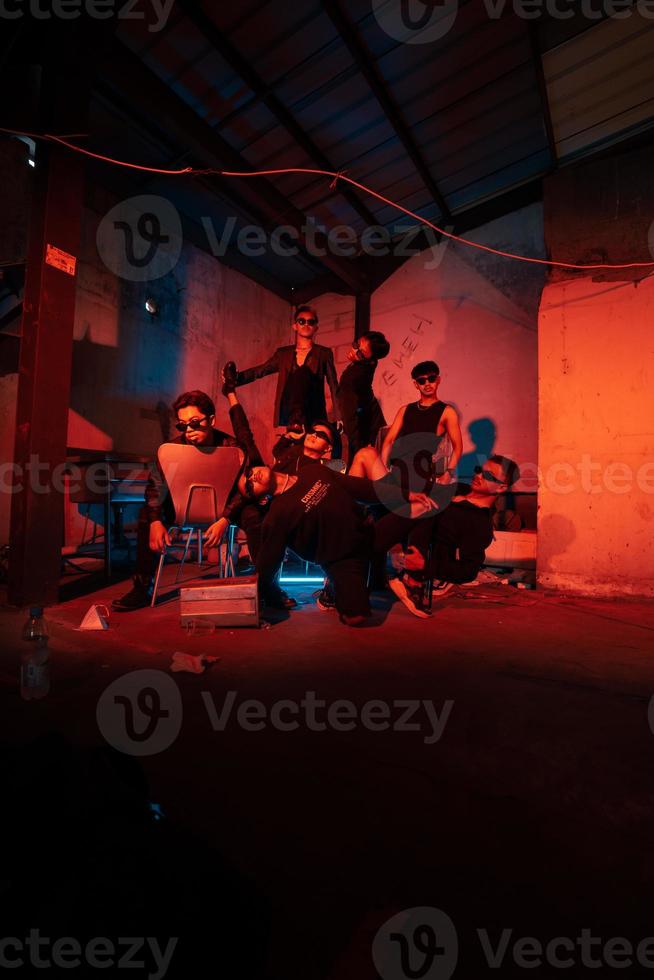 a group of thugs wearing dark clothes and glasses were having fun chatting with their friends in an old building photo