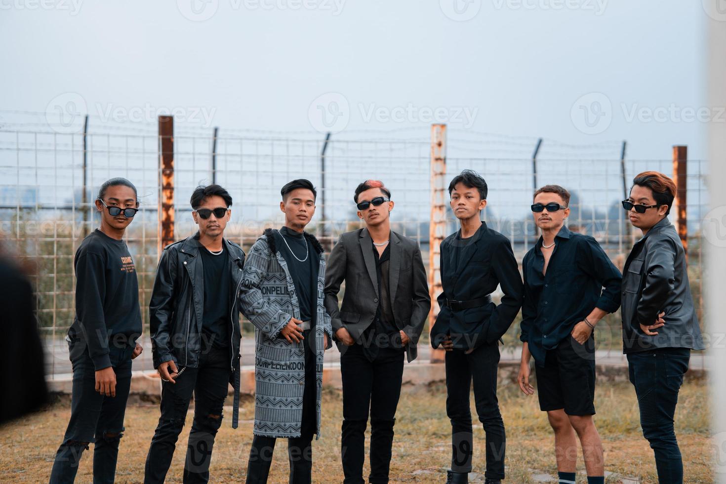 a group of teenage boys in black clothes posing very gallantly with their friends in a field photo