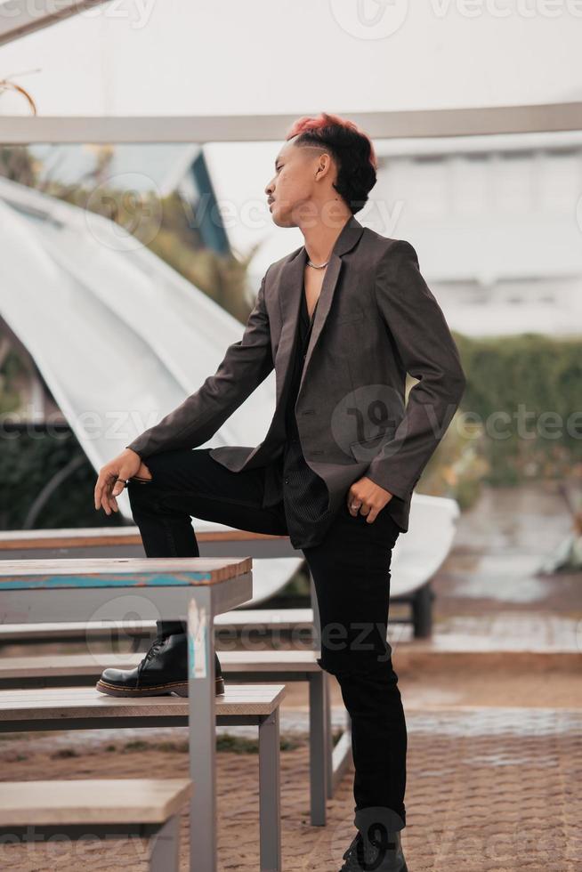 a grown man in a gray suit posing around a cafe table in a very manly and masculine manner before entering the office photo