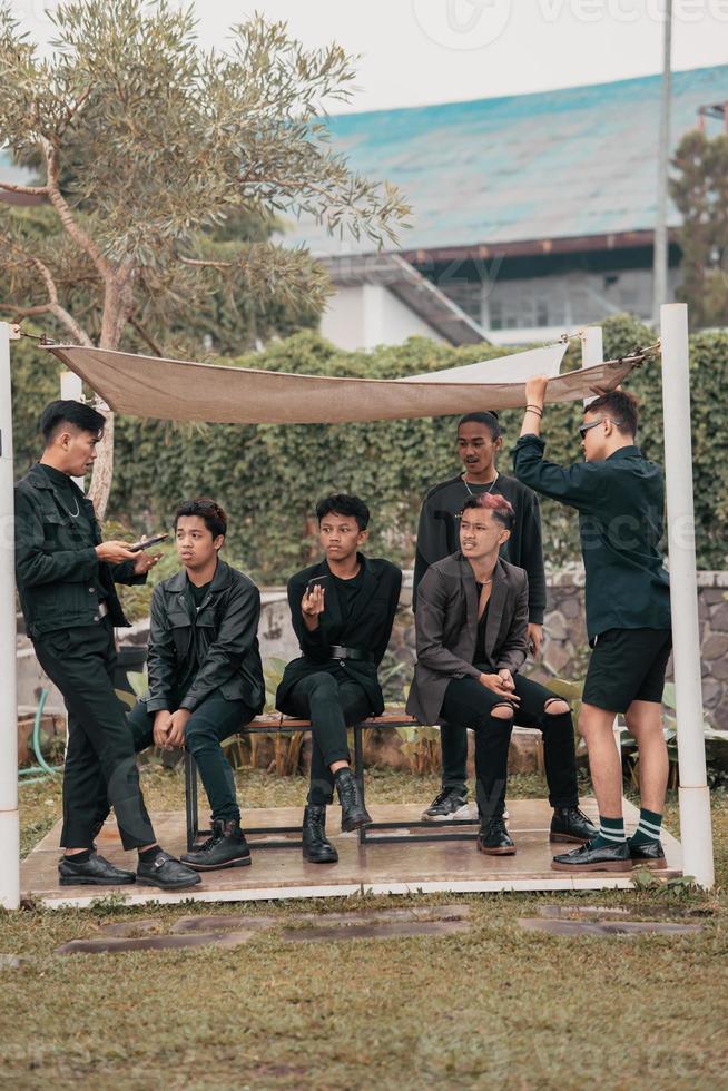 a group of Asian teenagers in black clothes stylized as naughty children while gathering at a cafe photo