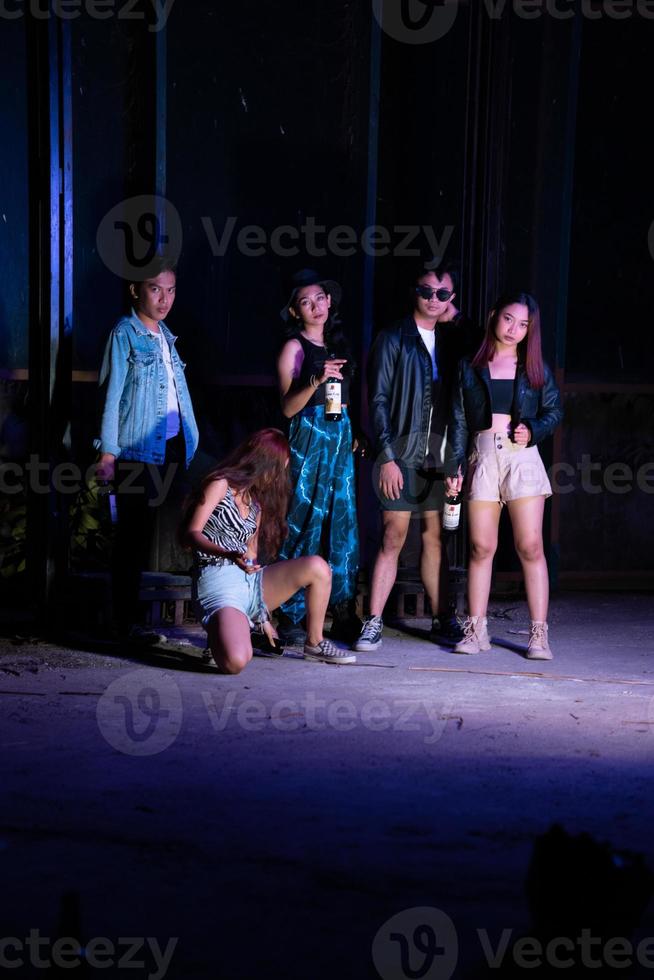 a group of teenagers taking a photo together with a purple light in front of a bar