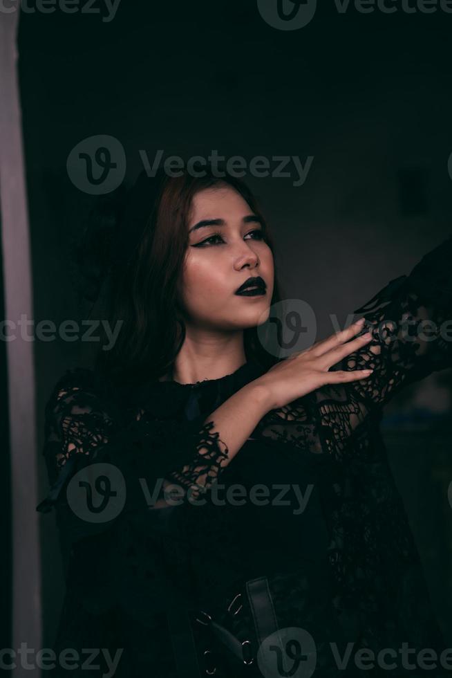 a scary Asian woman with black lips holding her all-black clothes when visiting the cemetery photo