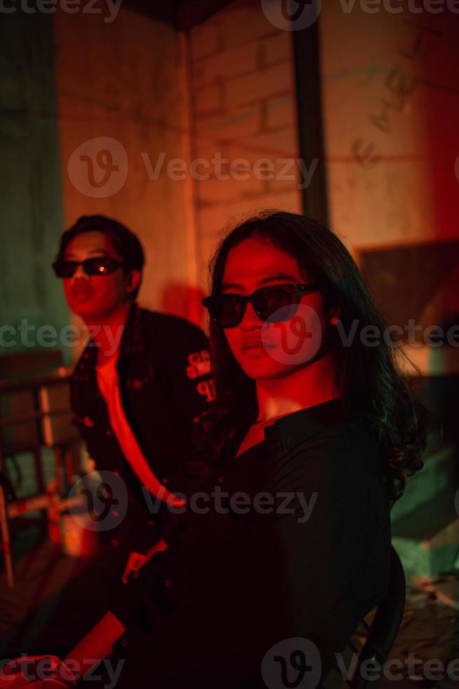 a stylish couple in black clothes are making out in an old barn with colorful lights photo