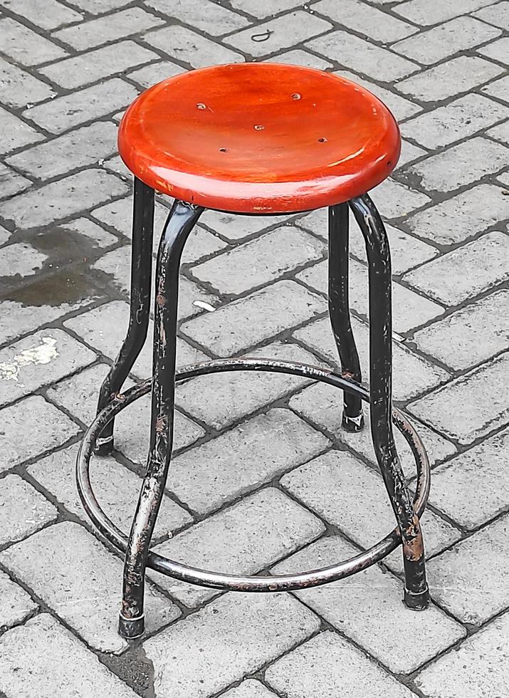 Close-up photo of a round iron chair with a wooden base