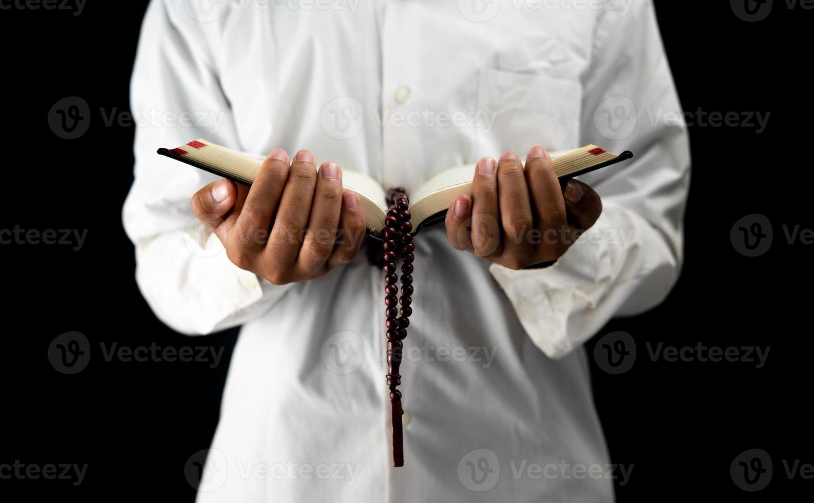 Man holding and reading holy Quran on black background photo